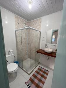 uma casa de banho com um chuveiro, um WC e um lavatório. em Pousada Vila Mar em Itaúnas