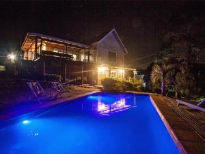 a swimming pool in front of a house at night at Chelsea Manor in Kini Bay