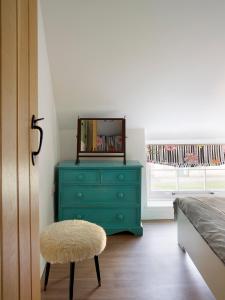 a bedroom with a blue dresser with a mirror and a stool at The Coach House - Market Deeping in Market Deeping