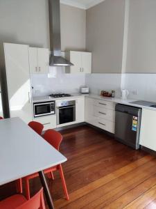 Il comprend une cuisine avec des placards blancs et du parquet. dans l'établissement North Perth Stylish Character Home Close CBD, à Perth
