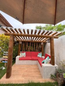 a red couch under a wooden pergola at Pousada Vila Mar in Itaúnas