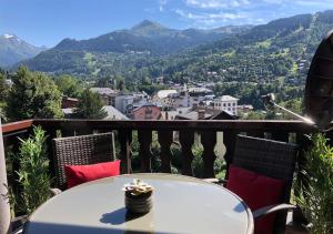 a table on a balcony with a view of mountains at Taragan - Totally Refurbished 3 bed apt, Central St Gervais! in Saint-Gervais-les-Bains