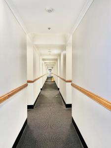 einen leeren Flur in einem Bürogebäude mit weißen Wänden in der Unterkunft Ensuite gouger entire apartment in Adelaide