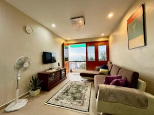 ein Wohnzimmer mit einem Sofa und einem TV in der Unterkunft The Rockview Bayu Emas Penang Near Beach in Batu Feringgi