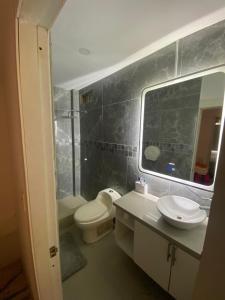 a bathroom with a toilet and a sink and a mirror at Casa ideal para familias estadías largas y cortas in Manta