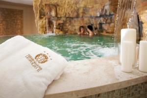 a couple in a swimming pool with a waterfall at Hotel Terme Marine Leopoldo II TERME & SPA in Marina di Grosseto
