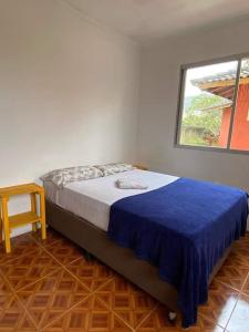 a bedroom with a bed with a blue blanket and a window at Amares Hostel in Florianópolis