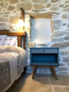 um quarto com uma cama azul e uma parede de pedra em Gîte Figuier au Mas Dujau em Saint-Sauveur-de-Cruzières