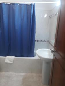 baño con cortina de ducha azul y lavamanos en STUDIO COMPLETO PARA 2 PESSOAS, en Albufeira