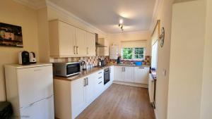 a kitchen with white cabinets and white appliances at Walma in West Runton