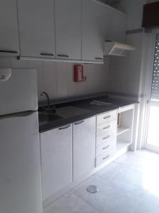 una cocina blanca con armarios blancos y fregadero en STUDIO COMPLETO PARA 2 PESSOAS, en Albufeira