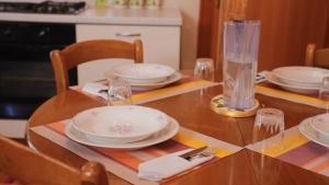 uma mesa de jantar com pratos, garfos e guardanapos em Accogliente Appartamento Foppolo em Foppolo