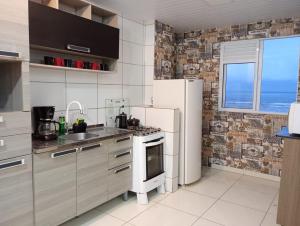 uma cozinha com um frigorífico e um lavatório em Apartamentos com Vista pro Mar de Imbituba residencial mar azul em Imbituba