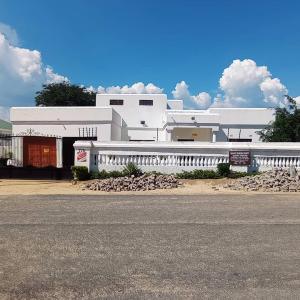 a white building with a street in front of it at WaterBerry Guest House in Kasane