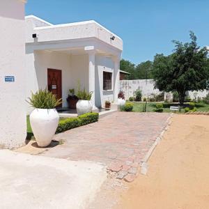 a house with two large white vases in front of it at WaterBerry Guest House in Kasane