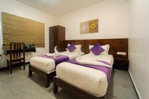 1 dormitorio con 2 camas con almohadas moradas y blancas en Hoppers Stop Yelahanka, en Bangalore
