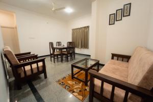 a living room with a couch and chairs and a table at Hoppers Stop Yelahanka in Bangalore