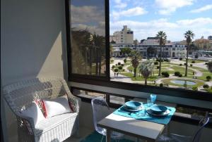d'un balcon avec une table, des chaises et une grande fenêtre. dans l'établissement Estoril Beach Side Casino Garden Apartment Cascais, à Estoril