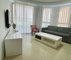Una sala de estar con un sofá y un televisor. en LOVELY 2BR GOLF RESIDENCE EILAT, en Eilat