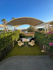 un patio con mesa y sillas en el césped en Le Rabelais, en Le Lavandou