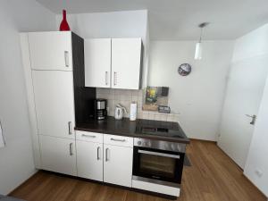 a kitchen with white cabinets and a stove top oven at Haus Alpina Ski In & Ski Out in Schladming