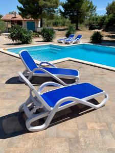 a pair of lounge chairs next to a swimming pool at Villa Tovarovica in Primošten
