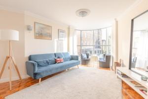 sala de estar con sofá azul y TV en Spacious 3BD Flat - 14 Mins to Buckingham Palace! en Londres