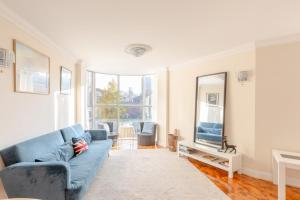 a living room with a blue couch and a tv at Spacious 3BD Flat - 14 Mins to Buckingham Palace! in London