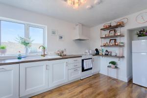 uma cozinha com armários brancos e um frigorífico branco em Holland House No1 em Liscannor