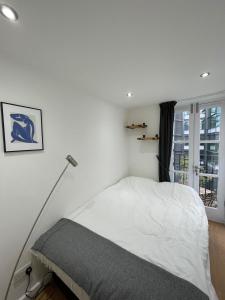 a white bedroom with a bed and a window at Stunning 3BD Maisonette wBalcony - Old Street! in London
