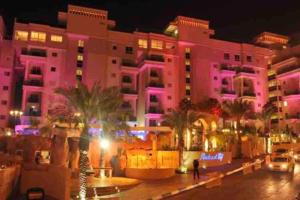 un edificio rosa con palmeras delante en LOVELY 2BR GOLF RESIDENCE EILAT, en Eilat