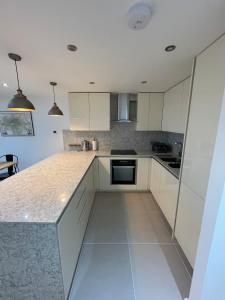 a kitchen with white cabinets and a counter top at Stunning 3BD Maisonette wBalcony - Old Street! in London