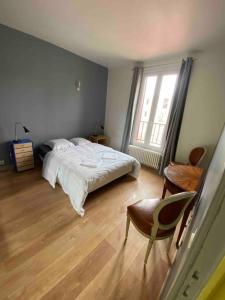 um quarto com uma cama, uma cadeira e uma janela em PARIS- Défense/Puteaux Appartement Cartault em Puteaux