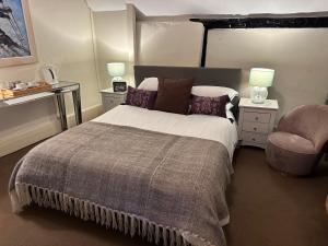 1 dormitorio con 1 cama grande y 1 silla en The Red Lion en Blewbury