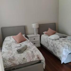 sypialnia z 2 łóżkami z poduszkami i stolikiem nocnym w obiekcie North Perth Stylish Abode CBD w mieście Perth