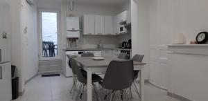 eine weiße Küche mit einem Tisch und Stühlen in der Unterkunft Bol d'air in Gravelines