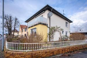 ein gelbes und weißes Haus mit einem Zaun in der Unterkunft Boettcher's Ferienwohnung in Neulußheim