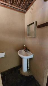 baño con lavabo y espejo en la pared en Charming Eco Cabin - Inhambane, en Ligogo