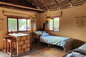 Habitación con cama, mesa y ventanas. en Charming Eco Cabin - Inhambane, en Ligogo