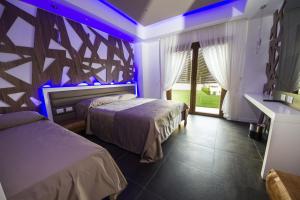 2 camas en una habitación con luces moradas en B&B Luna Per Te, en Rocca di Cambio