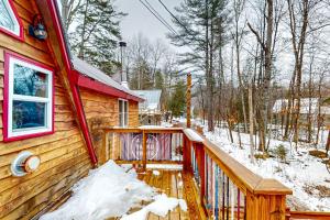 a cabin in the snow with a wooden deck at Sugarloaf Valley Escape in Carrabassett