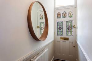 um espelho numa parede ao lado de uma porta em Tooting's Charming Victorian Garden Hideaway em Londres