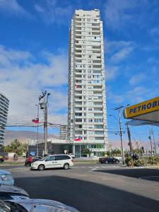 a white car parked in front of a tall building at Boulevard frente a la playa, Central y moderno in Iquique