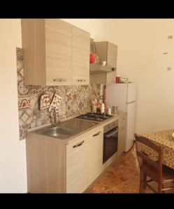 a kitchen with a sink and a stove and a refrigerator at Arco del vescovo 2 in Acireale