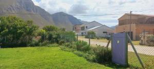 a fence in a yard with a mountain in the background at Cat Nap Cottage in Bettyʼs Bay