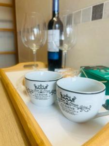 two cups sitting on a tray with a bottle of wine at Ático a 8 minutos de Toledo y 15 del Puy Du Fou in Bargas