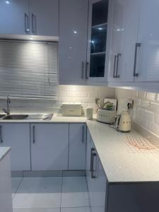 a white kitchen with white counters and white cabinets at Amazibuko Estate in Durban