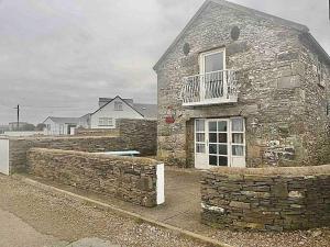 a stone house with a window and a stone wall at The Boathouse On The Atlantic Sea in Liscannor