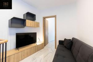 a living room with a couch and a flat screen tv at A lovely duplex maisonette just of Spinola w/WIFI by 360 Estates in St. Julianʼs