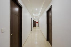 um corredor com portas pretas e paredes brancas em Super Townhouse 1291 Akshay Hotel em Gurgaon